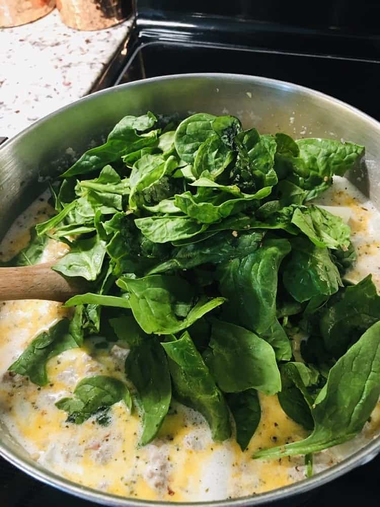 A bunch of spinach leaves are added into the soup.