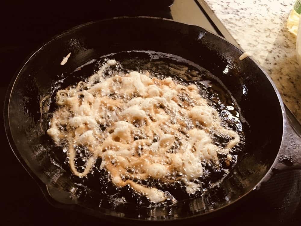 The funnel cake is slowly turning brown on the sides.