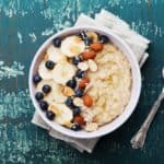 A bowl of healthy porridge that has fruits and nuts.