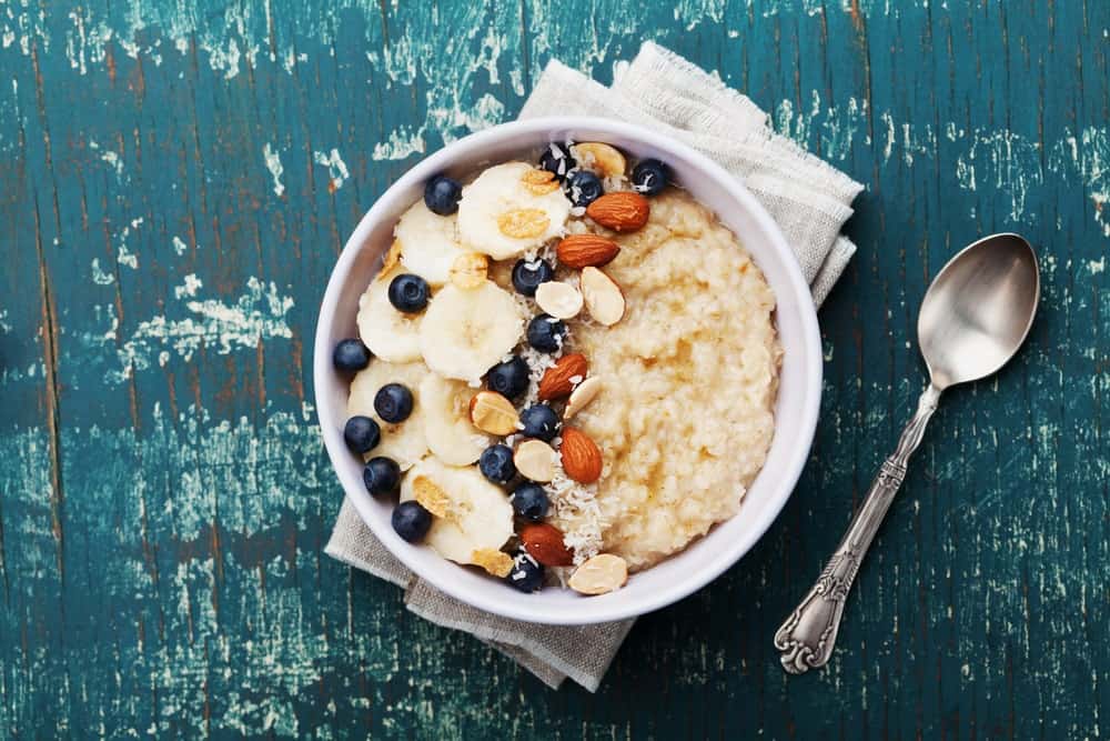 A bowl of healthy grits that has fruits and nuts.
