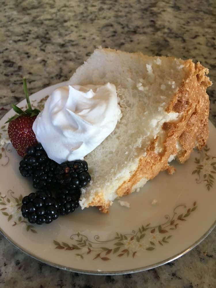 A freshly-baked slice of angel food cake with frosting and berries.