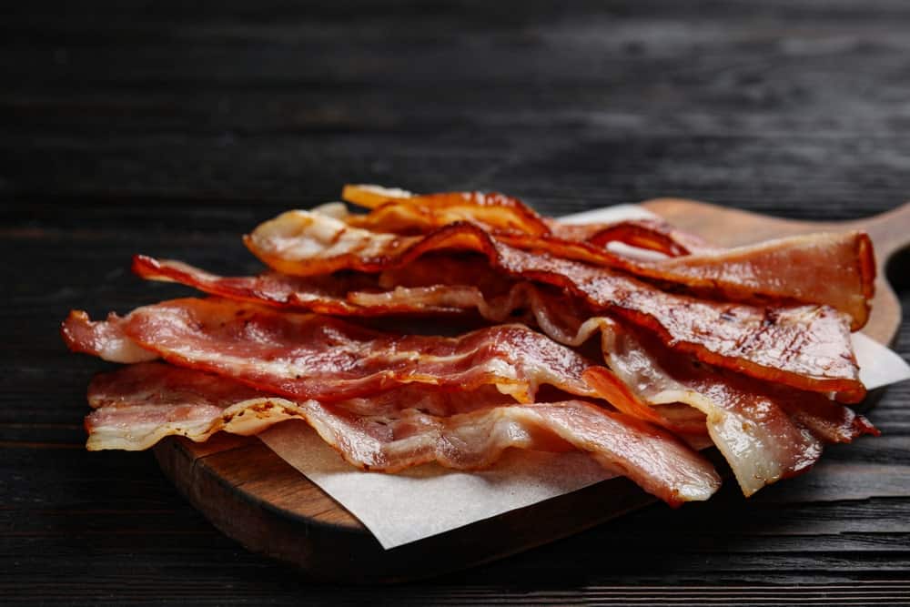 Slices of crispy fried bacon on a chopping board.