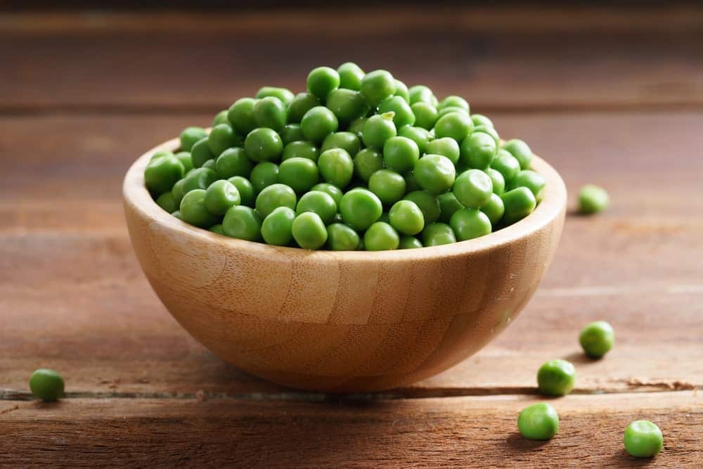 A wooden bowl of green peas.