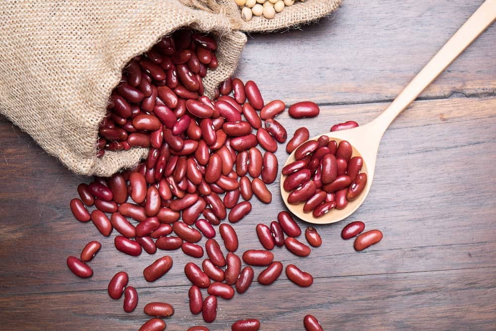 A sack of red beans with a wooden spoon.