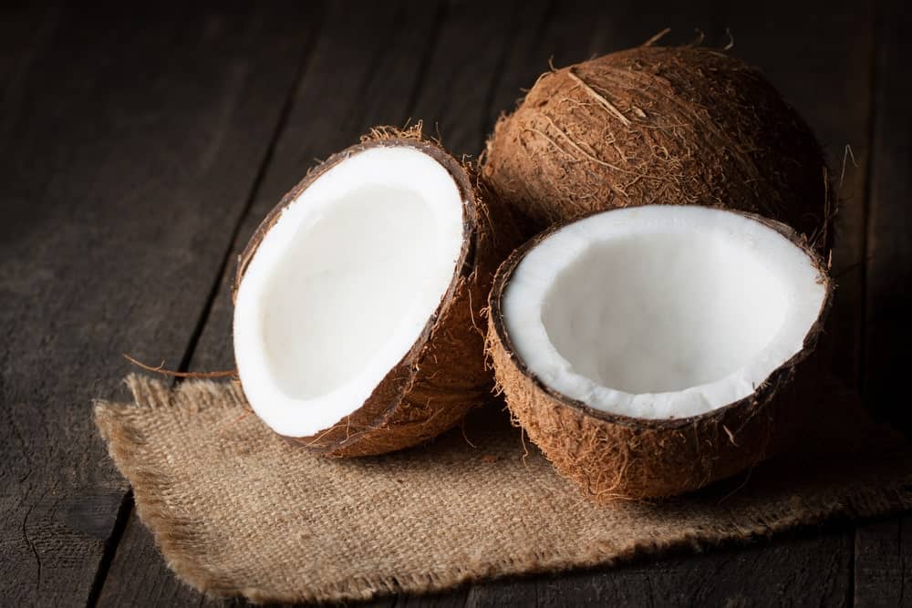 Coconut halves on a wooden table.