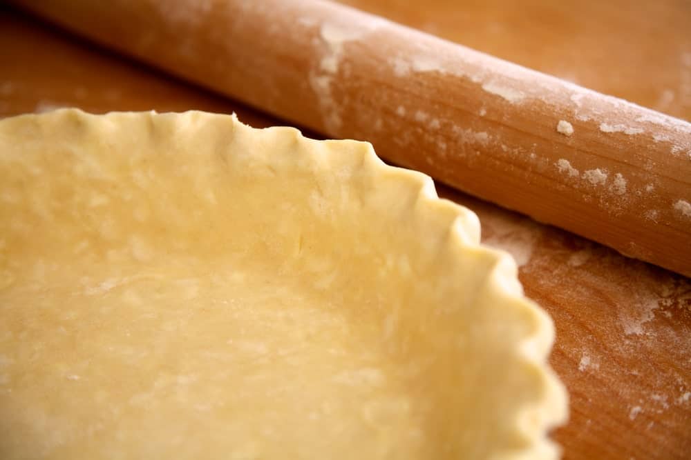 A close look at a pie crust dough with a rolling pin.