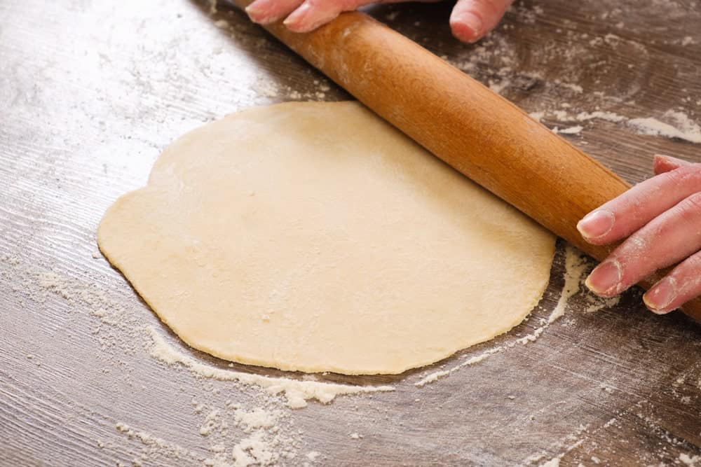 This is a look at an unleavened dough being flattened by a rolling pin.