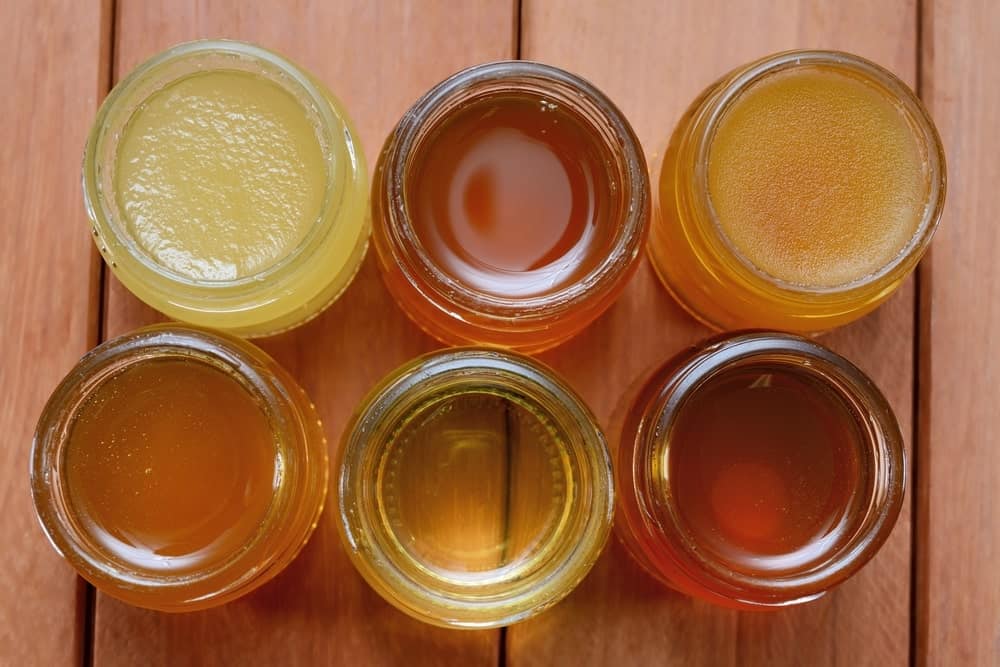 Different varieties of honey in separate glass jars.