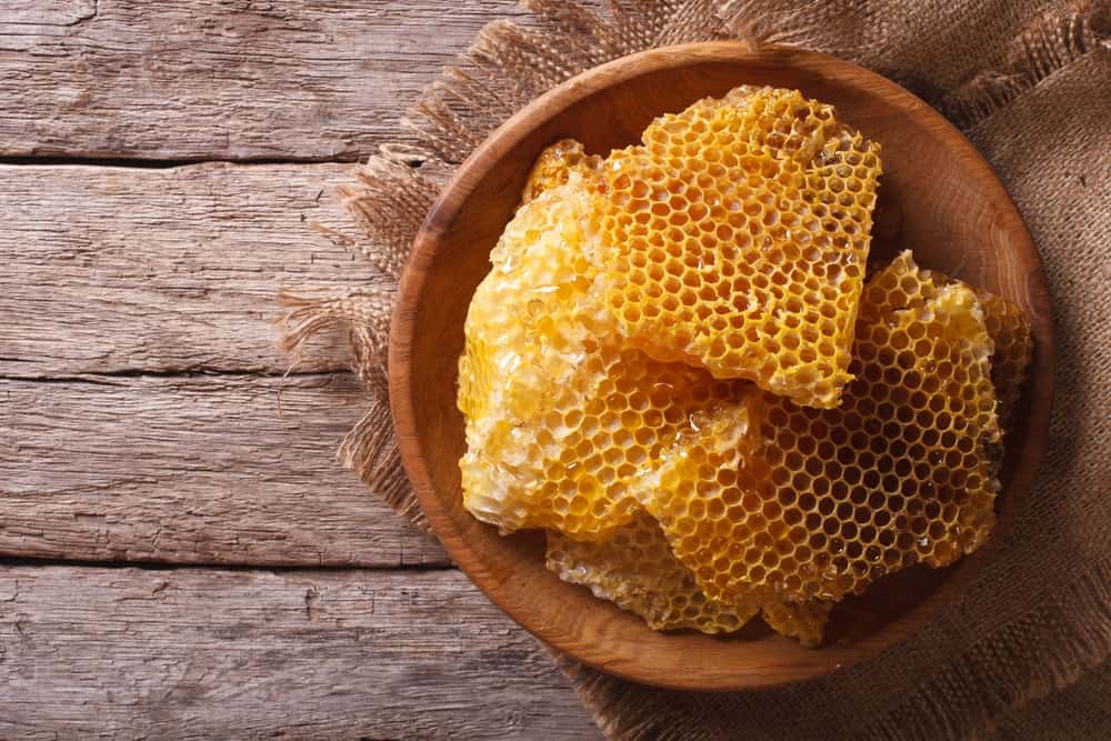 A wooden bowl of golden honeycomb.
