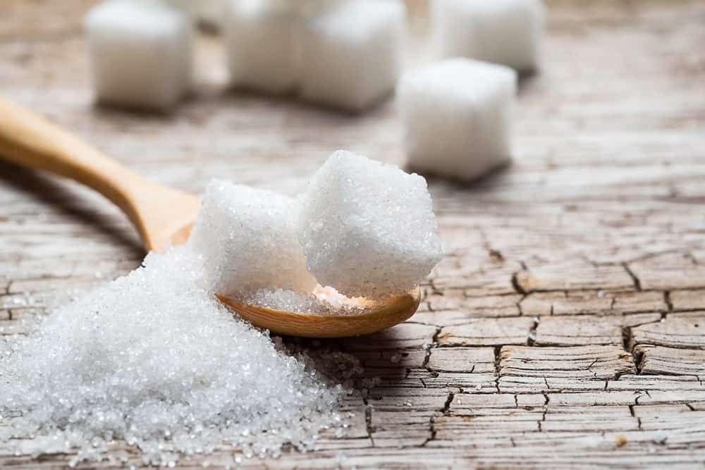 A close look at granulated white sugar on a wooden spoon.