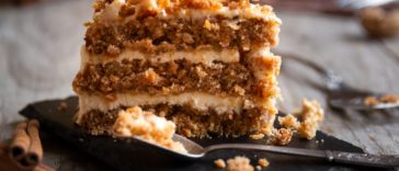A look at a slice of carrot cake that is topped with walnuts.
