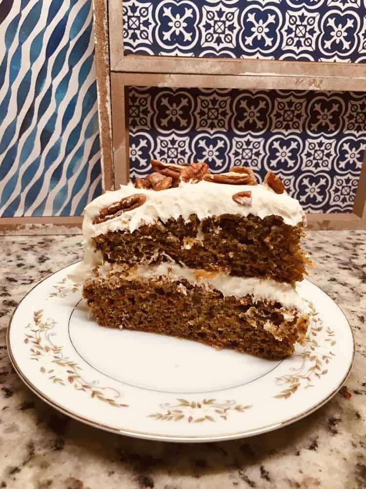 A slice of freshly-baked carrot cake topped with walnuts.