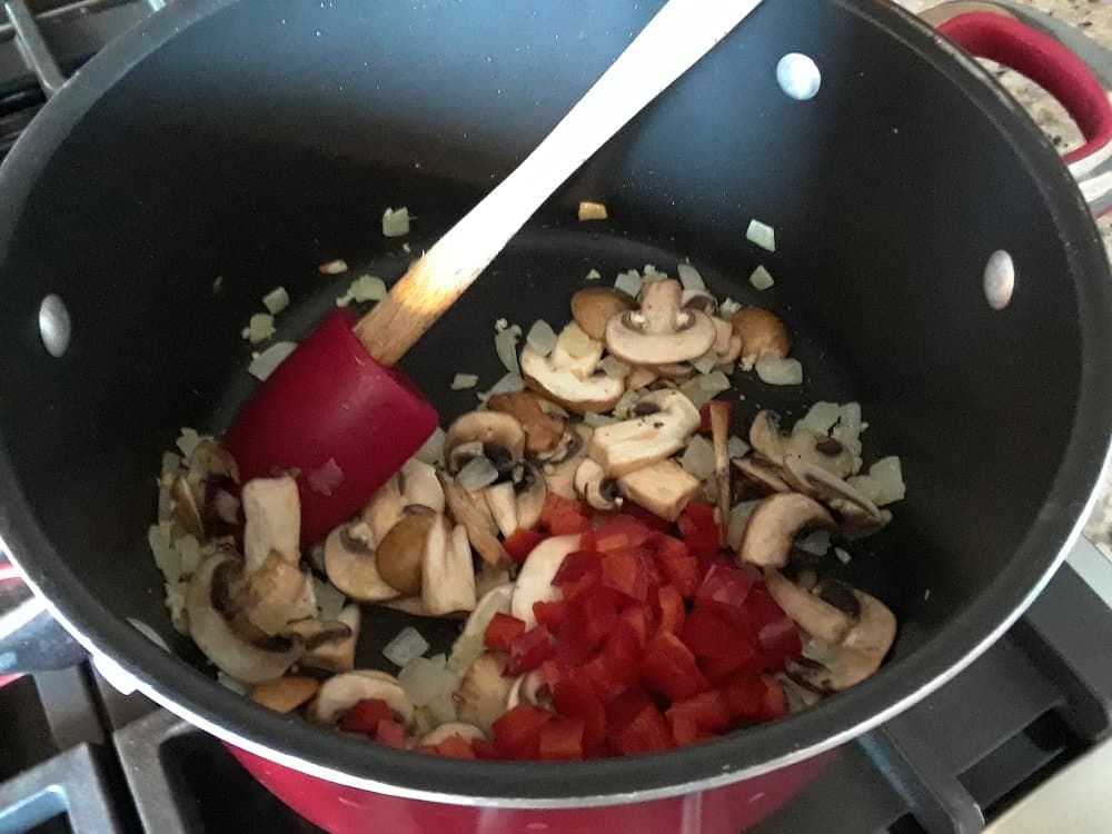 The first ingredients are being sauteed in a pot with oil.