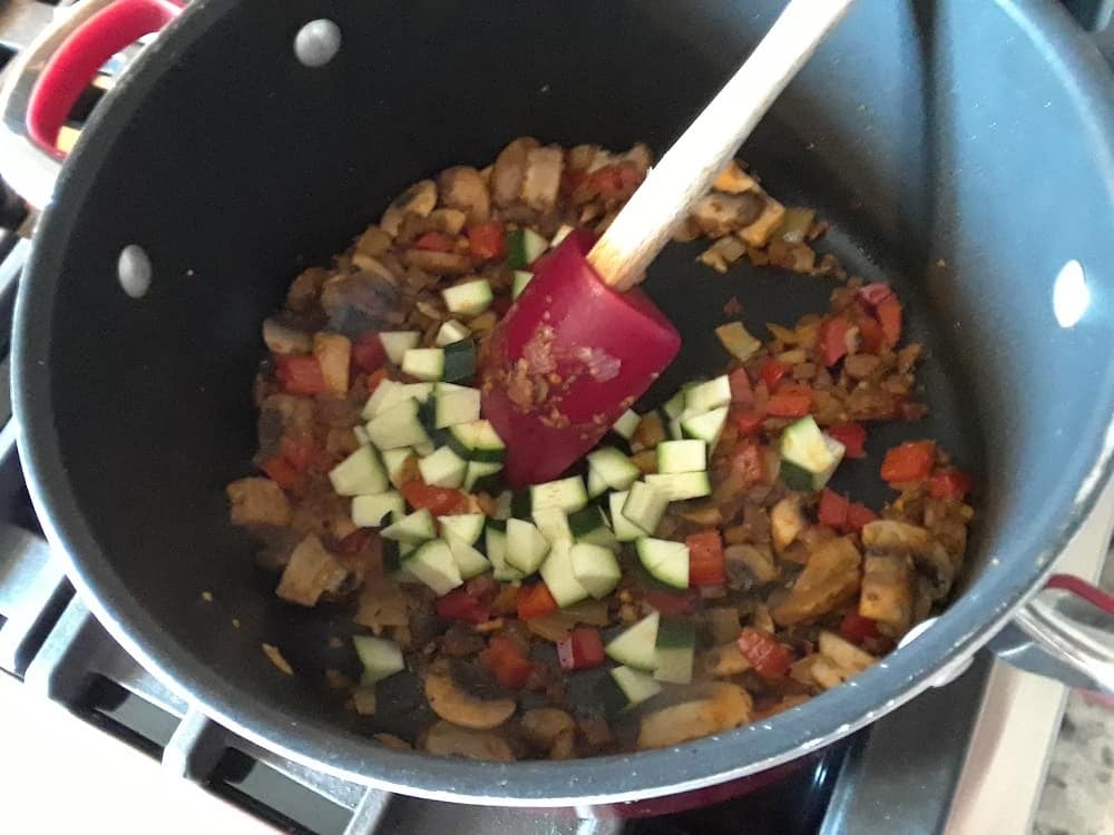 The zucchini is added into the sauteed ingredients.