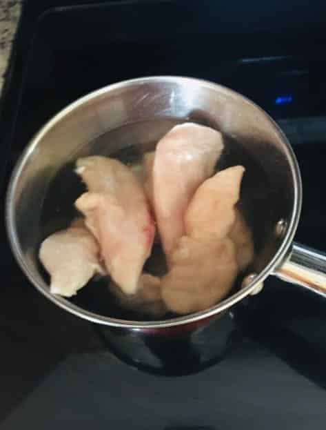 The chicken is boiled in a pot of water.