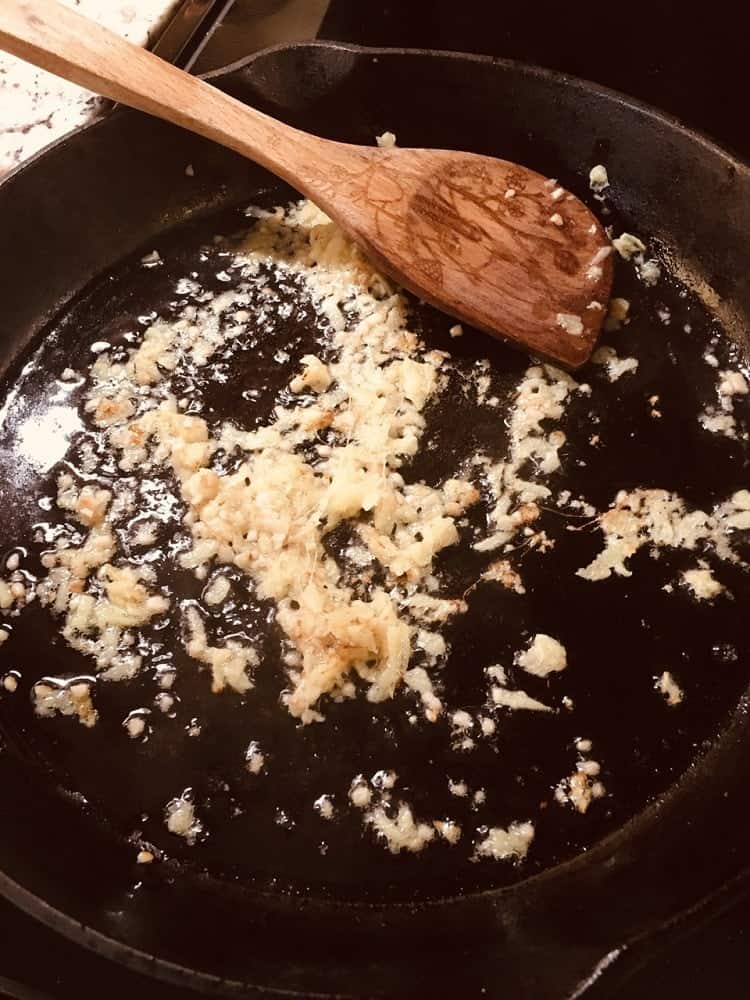 The garlic is being sauteed in a skillet.