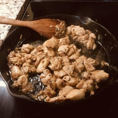 The marinated chicken is then added into the skillet with the spices.