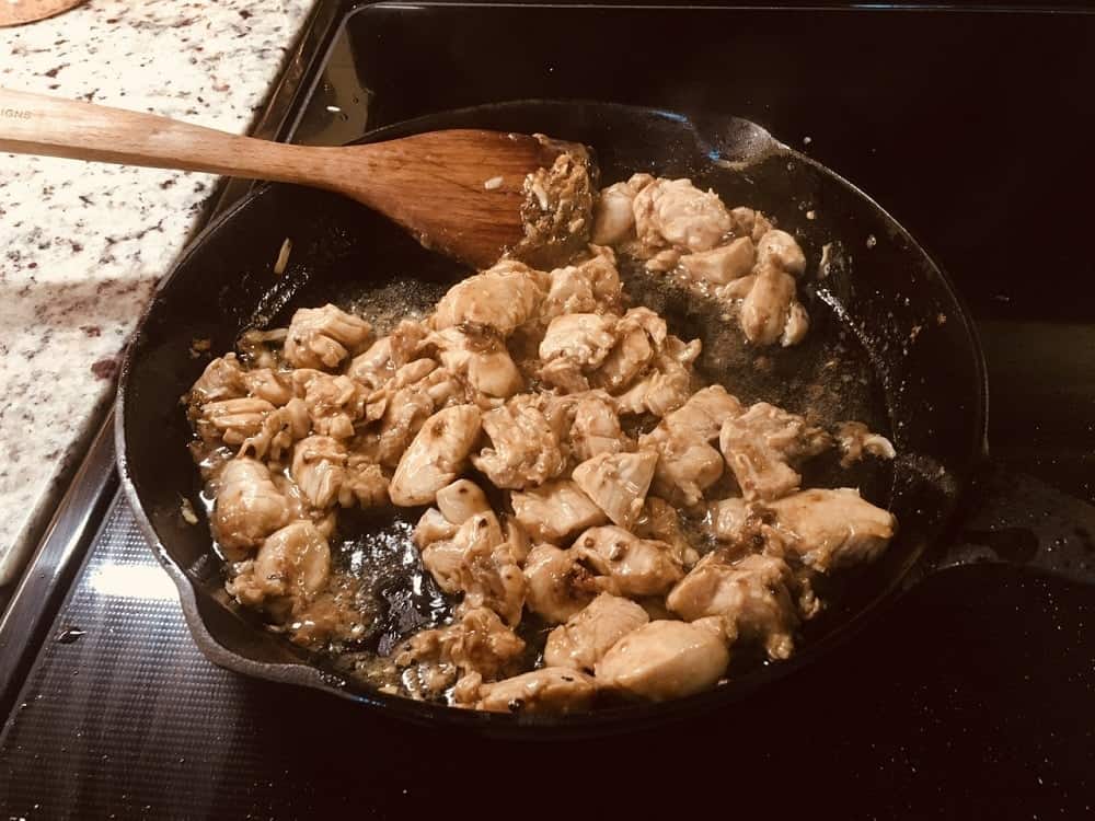 The marinated chicken is then added into the skillet with the spices.
