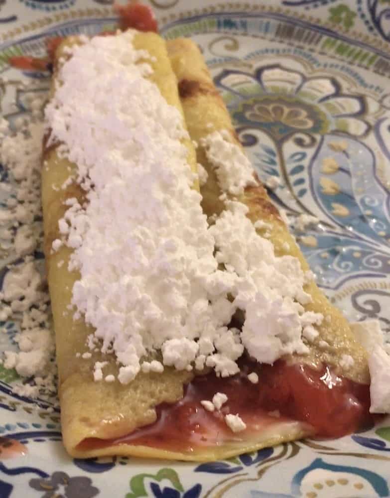 A plate of decadent strawberry cream cheese crepe.
