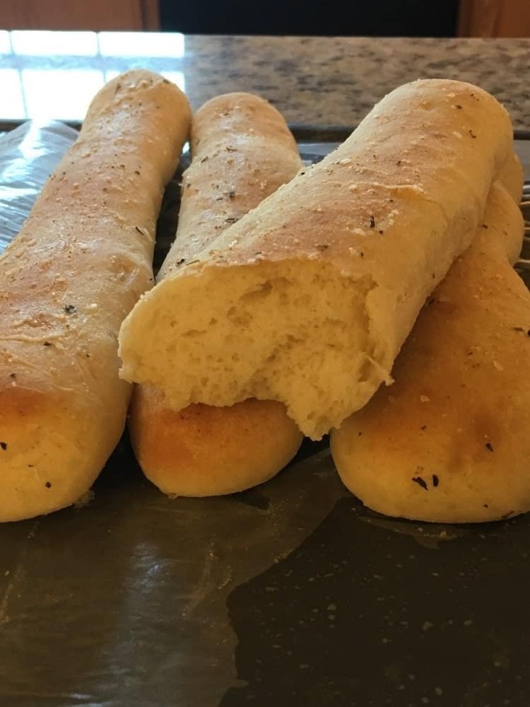 A stack of freshly-baked garlic and herb breadsticks.
