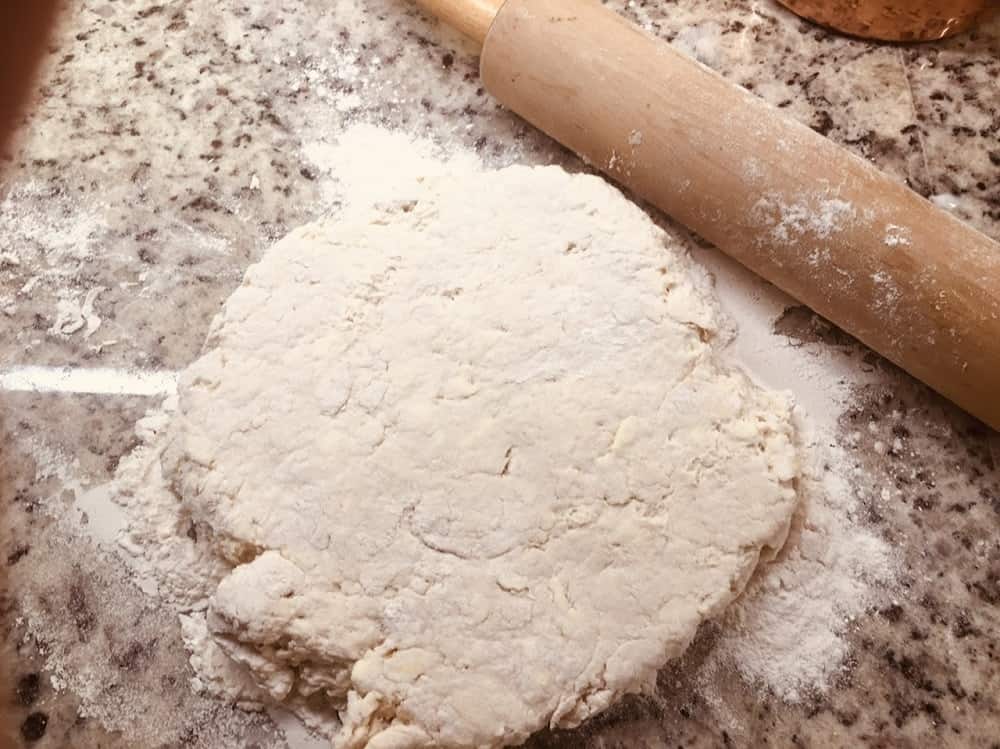 The dough is slightly flattened with a rolling pin.