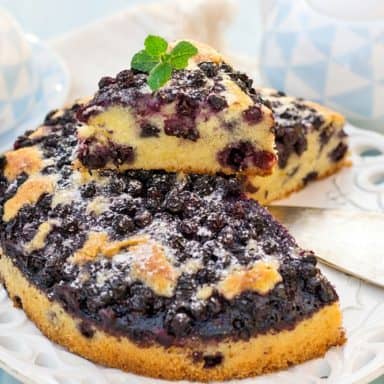 A sliced lemon blueberry coffee cake garnished with mint leaves on top.