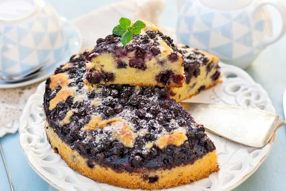 A sliced lemon blueberry coffee cake garnished with mint leaves on top.