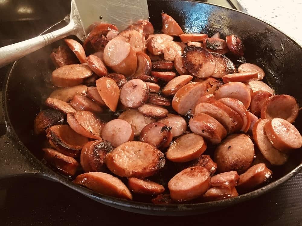 The sausage slices are sauteed in a skillet.