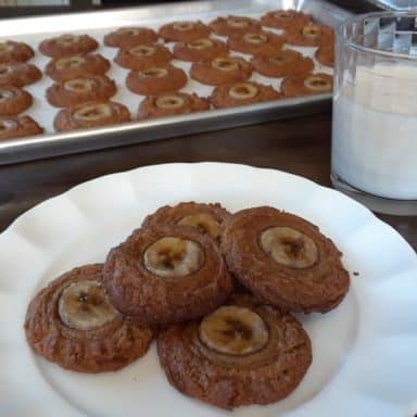 A plate of vegan peanut butter and banana cookies with a glass of milk.