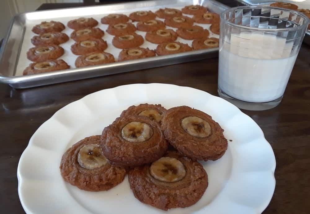 A plate of vegan peanut butter and banana cookies with a glass of milk.