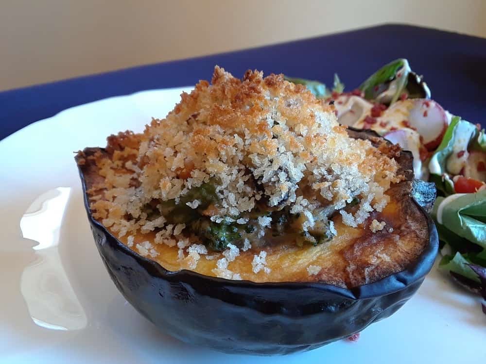 A plate of stuffed acorn squash with a side of salad.