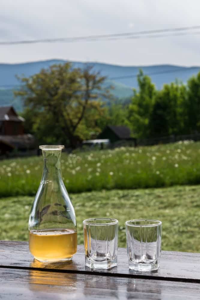 A glass bottle of show mead with a couple of glasses.