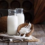 A couple of bottle of coconut milk with fresh coconuts.