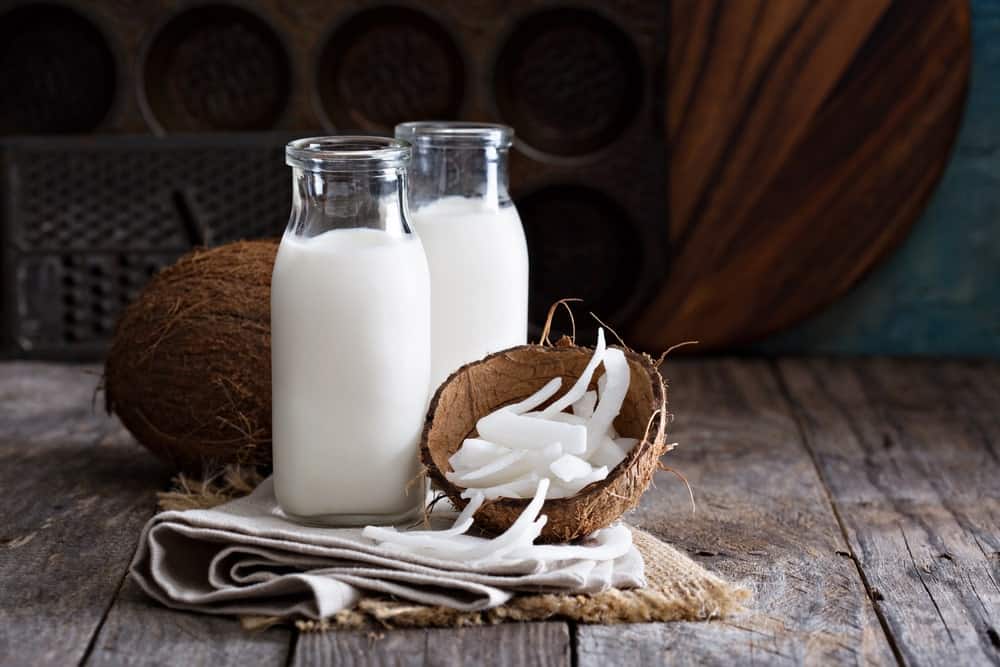 A couple of bottles of coconut milk with fresh coconuts.