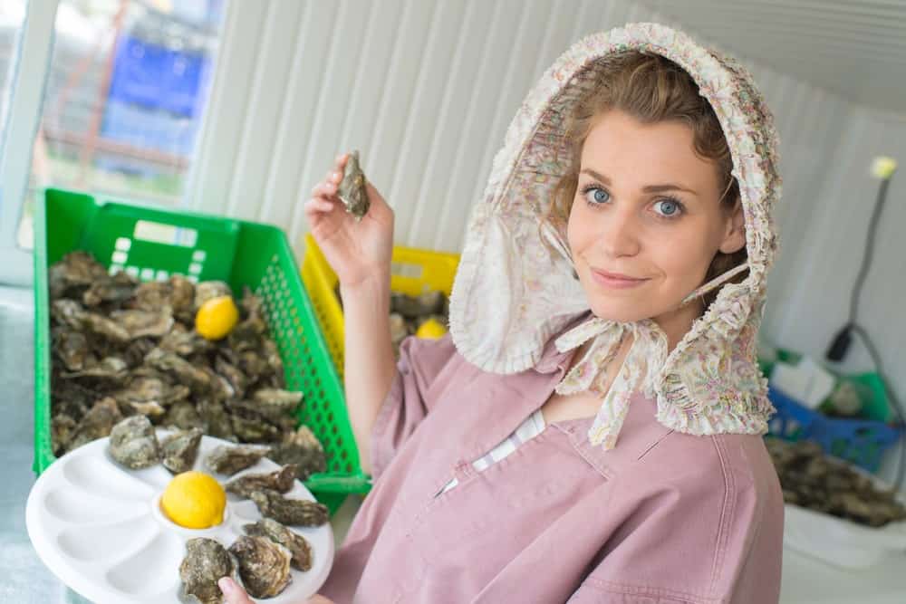 A woman choosing oysters from a bin.