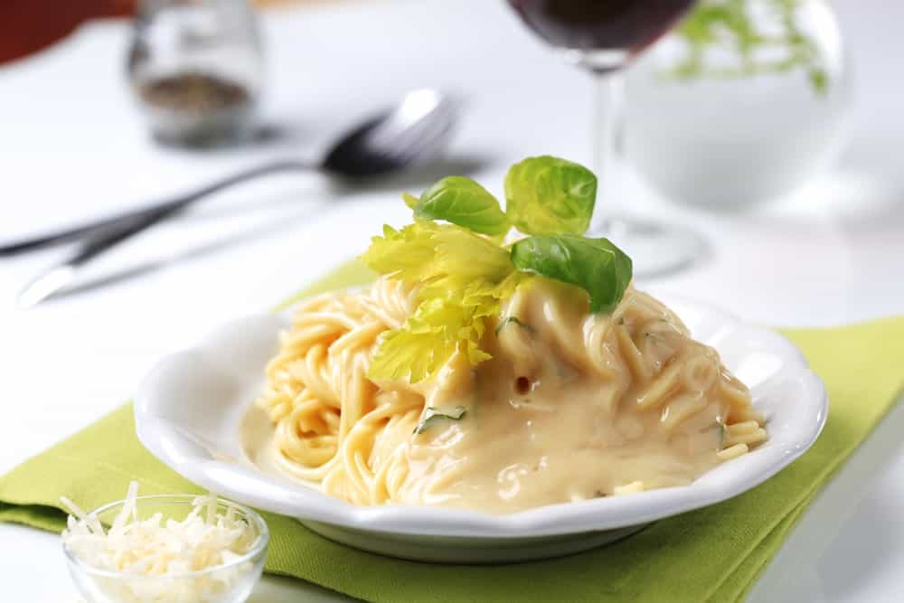 A plate of Bechamel pasta with fresh basil leaves on top.