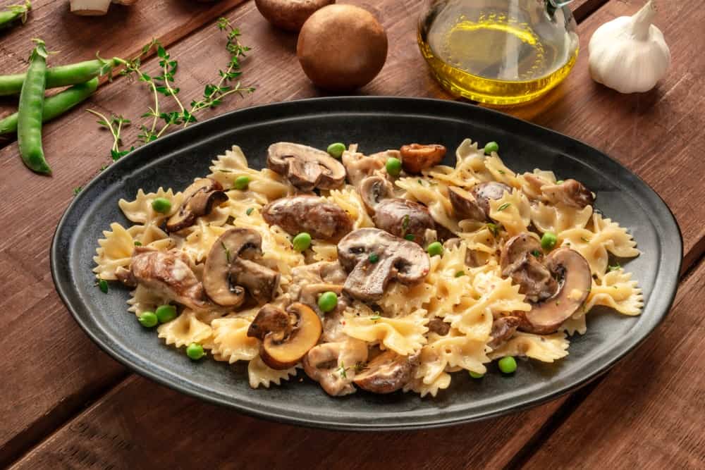 A plate of Funghi e Piselli with pieces of sliced mushroom, peas and ribbon pasta.