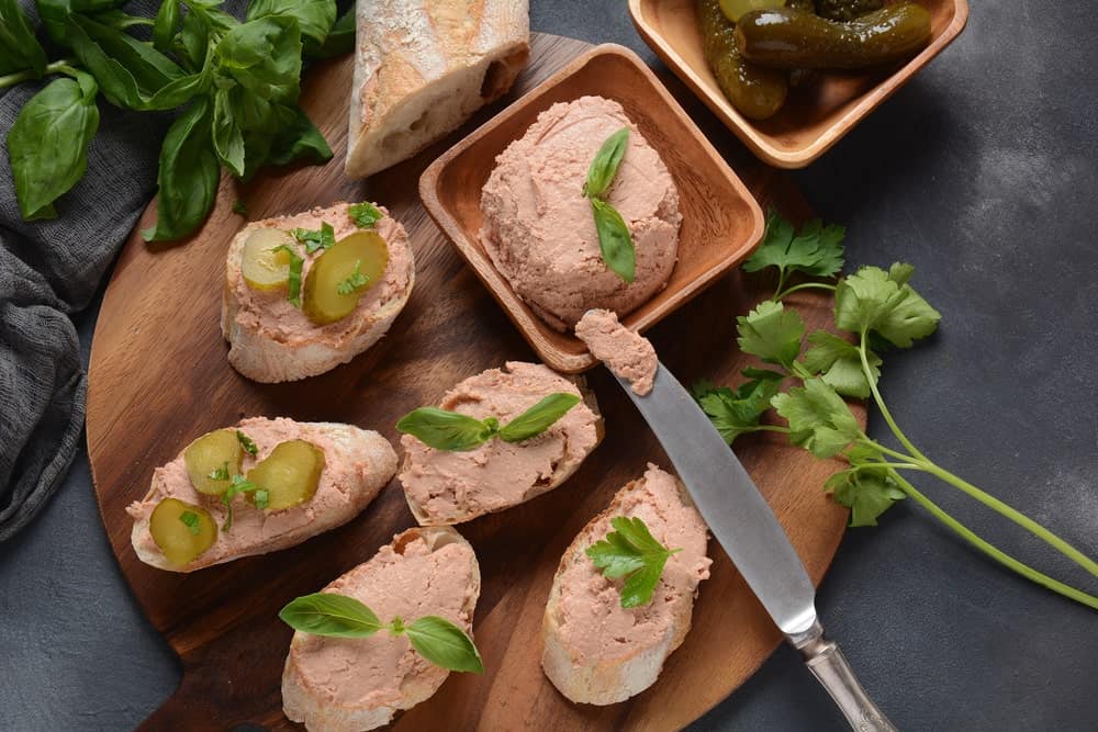 Chicken liver pate sandwiches on a wooden chopping board.