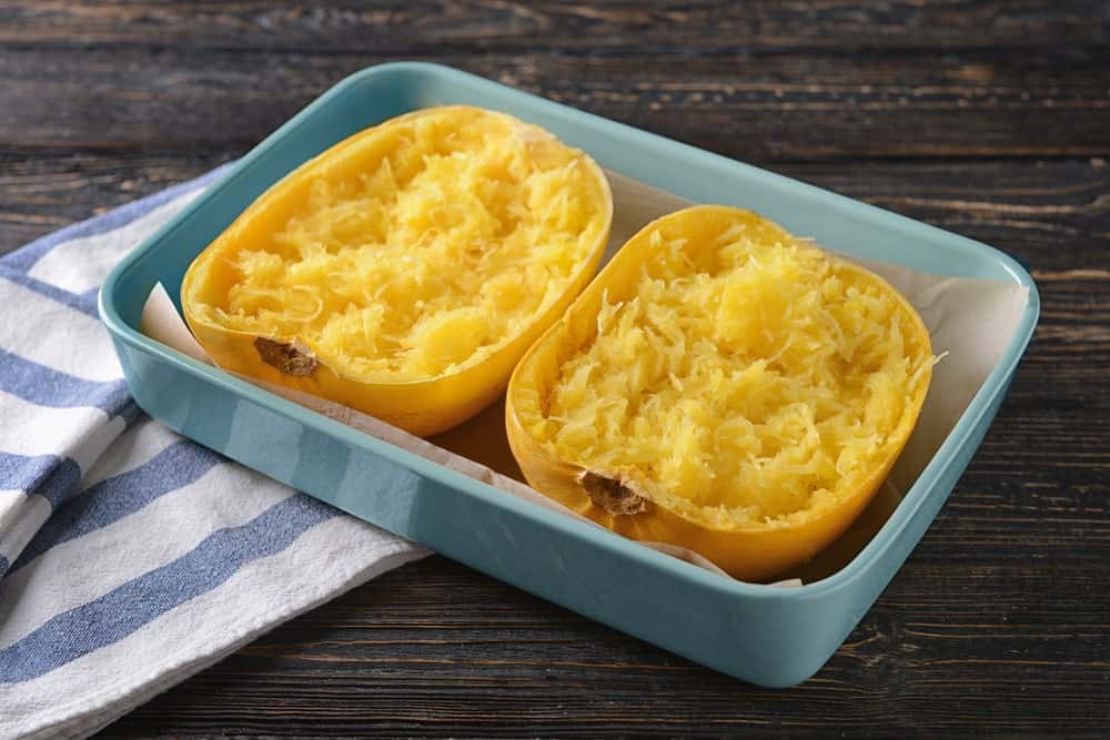 Spaghetti squash placed in a light blue pan to be baked.