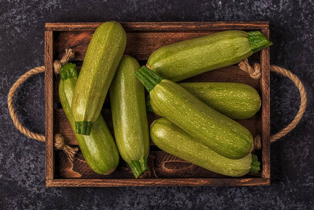A wooden tray of fresh zucchini squash.