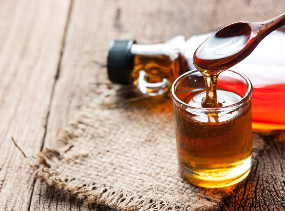 A close look at a maple syrup being spooned off a small glass.