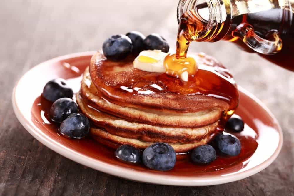 Maple syrup poured onto a stack of pancakes.