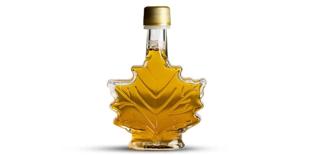 A close look at golden maple syrup in a leaf-shaped bottle.