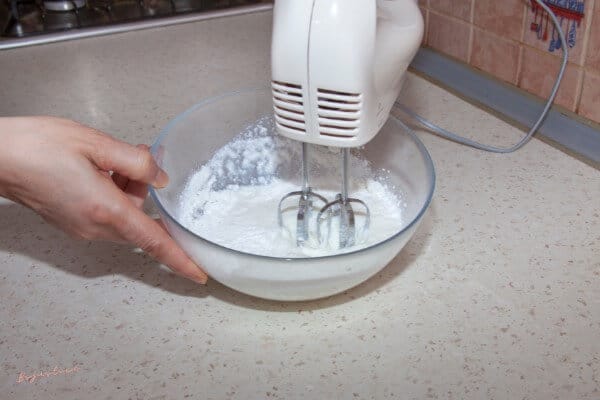 bowl of whipped cream being whipped by a hand mixer