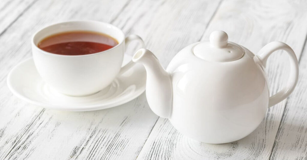a cup of hot tea brewed in a teapot