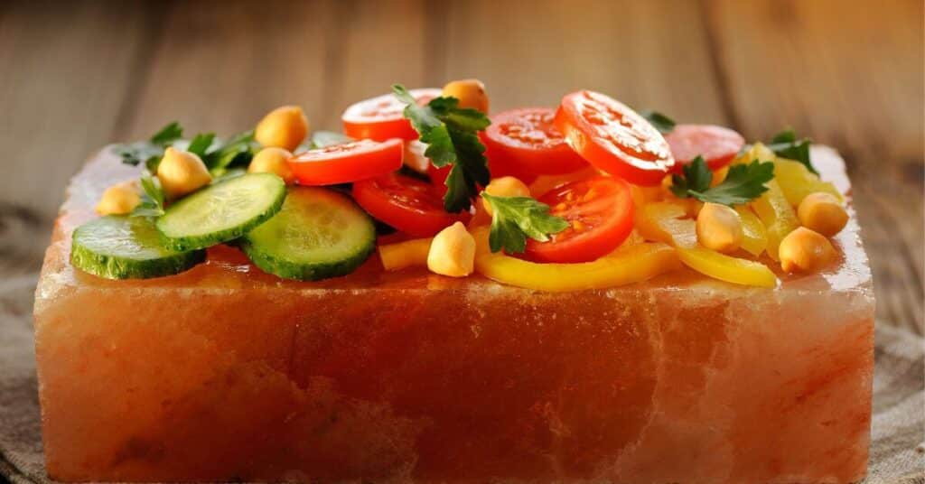 cooked vegetables on a pink salt block