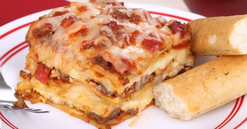 piece of homemade lasagna with breadsticks