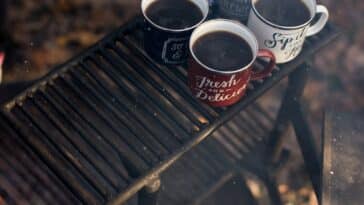 four assorted-color ceramic mugs on black grill frame